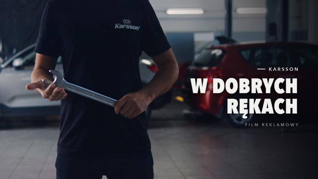 Mechanik w koszulce Karsson trzyma duży klucz płaski w warsztacie samochodowym, kadr z filmu reklamowego 302 Studio