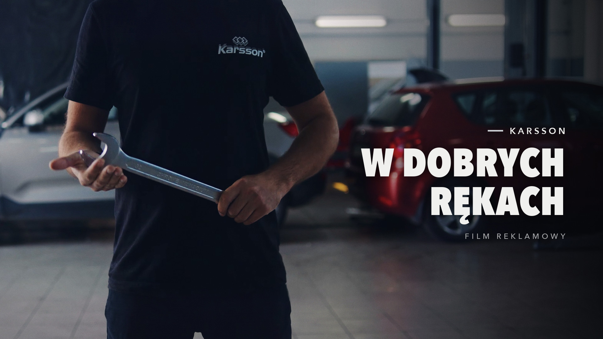 Mechanik w koszulce Karsson trzyma duży klucz płaski w warsztacie samochodowym, kadr z filmu reklamowego 302 Studio